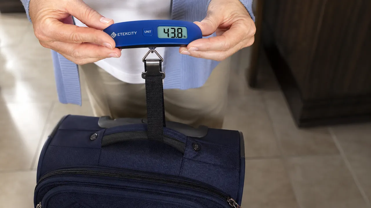 Etekcity digital luggage scale hooked onto a suitcase handle, displaying a weight reading in pounds